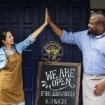 business owners standing with open blackboard